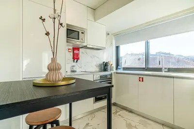 a kitchen with white cabinets and a vase on a counter at Large Terrace in Paraiso III in Porto