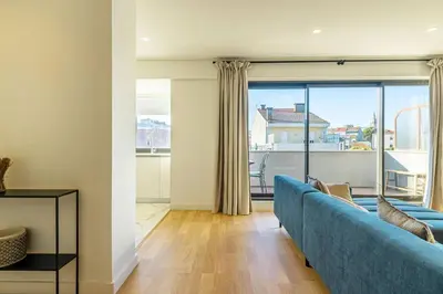 a living room with a blue couch and a large window at Large Terrace in Paraiso III in Porto