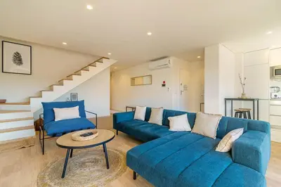 a living room with a blue couch and a table at Large Terrace in Paraiso III in Porto