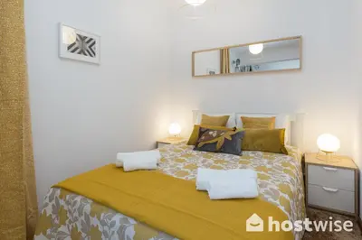 a bedroom with a large bed with a yellow blanket at Host Wise - Comfy Bright Flats with Netflix in Porto