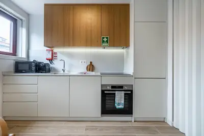 a kitchen with white cabinets and a sink and a stove at Nomads Lux - 1BDR Charming Top Floor Porto in Porto