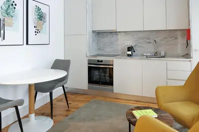 a kitchen with white cabinets and a yellow chair at Trindade Apartments by PHC in Porto