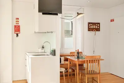 a kitchen with a table and a white refrigerator at Host Wise - Lovely Shinny Flats with Balcony - Clerigos in Porto
