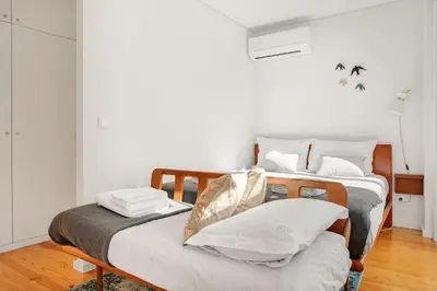 two beds in a room with white walls and wood floors at Host Wise - Lovely Shinny Flats with Balcony - Clerigos in Porto