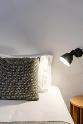 a bed with a pillow and a lamp on it at Miragaia Apartments by DA'HOME in Porto