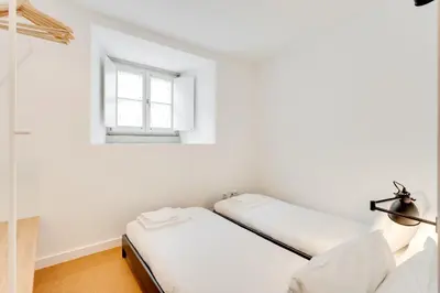 two beds in a room with a window at Miragaia Apartments by DA'HOME in Porto