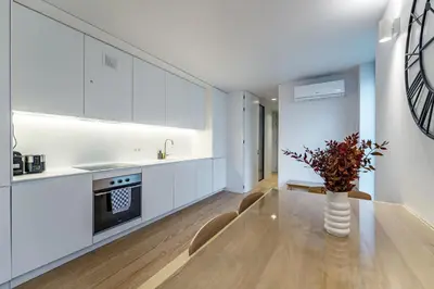 a kitchen with white cabinets and a vase of flowers on a table at Nomad's Lux - Almada Apartments Porto in Porto