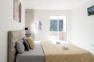 a bedroom with a bed with two white shoes on it at Host Wise - Spacious Noble Apartaments Ace Location in Porto