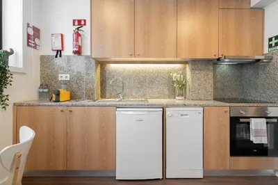 a kitchen with white appliances and wooden cabinets at Host Wise - Modern Studios with Terrace - Walk Everywhere in Porto