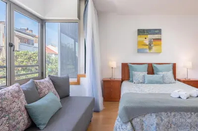 a bedroom with a bed and a couch and a window at Host Wise - Bright Quiet Flats - Prime Location in Porto
