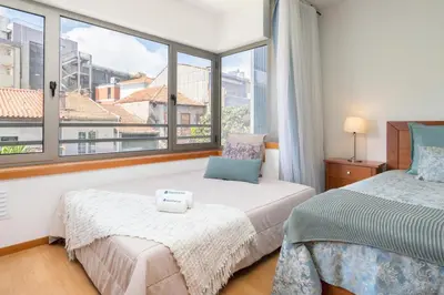 a bedroom with two beds and a large window at Host Wise - Bright Quiet Flats - Prime Location in Porto