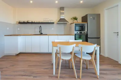 a kitchen with a wooden table and white chairs at Host Wise - Fantastic Contemporary Flat w Balcony in Porto