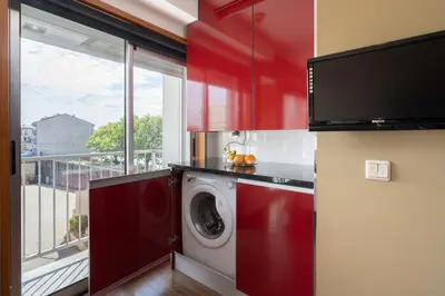 a kitchen with red cabinets and a washing machine at Host Wise - Bright Fresh Flat with Garage - Marquês in Porto