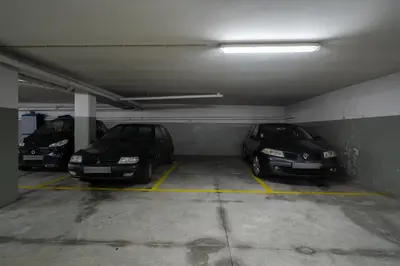 a parking garage with three cars parked in it at Host Wise - Bright Fresh Flat with Garage - Marquês in Porto
