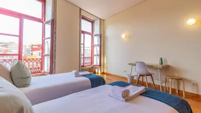 a room with two beds and a desk with a balcony at Bento Living by LovelyStay in Porto