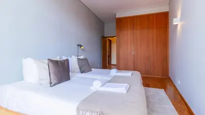 a bedroom with a large white bed and a wooden cabinet at Bento Living by LovelyStay in Porto