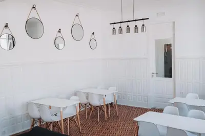 a room with white tables and chairs and mirrors at OLOPO Hostel in Porto