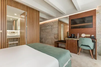 a bedroom with a bed and a desk and a television at Ribeira Douro Hotel in Porto