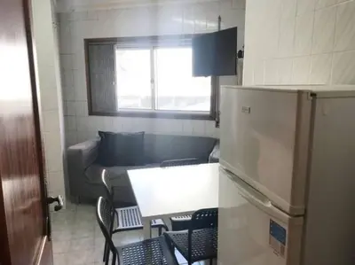 a small kitchen with a table and a refrigerator at Covelo 90 in Porto