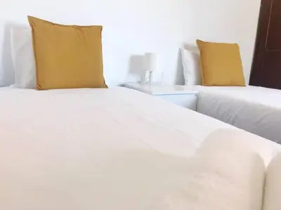 a bedroom with two beds with white sheets and yellow pillows at Covelo 90 in Porto