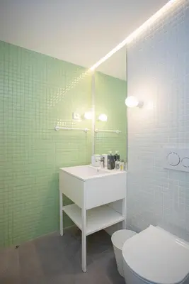 a bathroom with a sink and a toilet and green tiles at Allegro Boutique Apartments by Liiiving in Porto