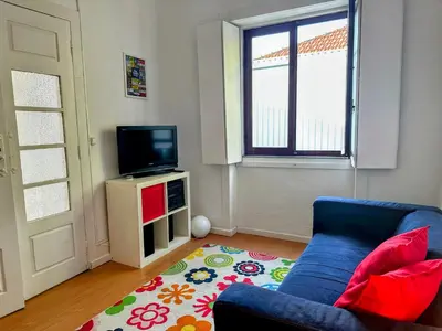 a living room with a blue couch and a television at Figueiroa 10 in Porto