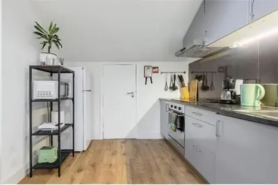 a kitchen with white cabinets and a wooden floor at Gaia Style Room in a Shared Apartment in Vila Nova de Gaia