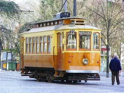 a yellow trolley car on a street with a man walking by at Apartment with Private Garden in Porto