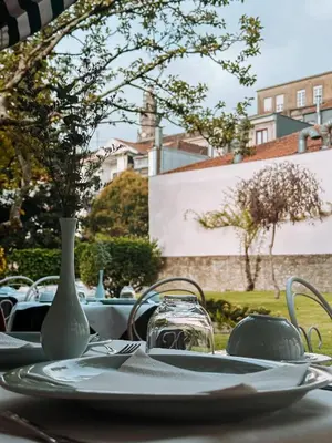 a table with a white vase and plates on it at GRANDE HOTEL PARIS by STAY HOTELS in Porto