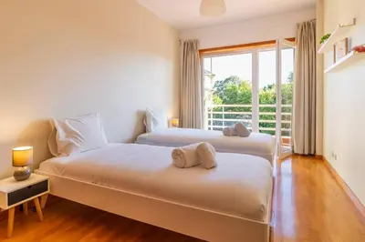 two beds in a room with a window at Casa da Praça in the center of Porto - GuestSPA in Porto
