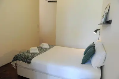 a small bedroom with a white bed with pillows at Porto City Center Mercado do Bolhão Prime location jesuína e as 3 janelas in Porto
