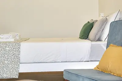 a bedroom with a white bed with pillows and a couch at Oporto Sweet Downtown 2 in Porto