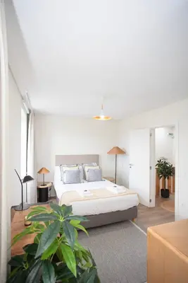 a white bedroom with a bed and a plant at Liiiving in Porto - Downtown Quiet House in Porto