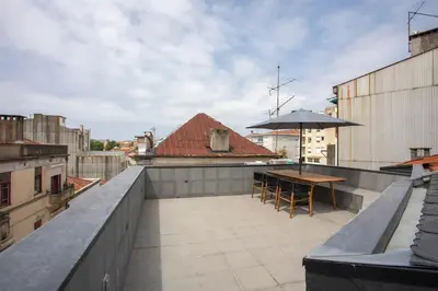 a patio with a table and an umbrella on a roof at Liiiving in Porto - Cedofeita Green Terrace in Porto