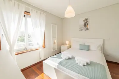 a white bedroom with a bed and a window at Modern Cedofeita by Hosty in Porto