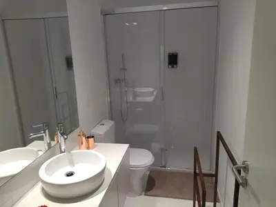 a white bathroom with a sink and a shower at Cais das Pedras Pátio Apartment - with washer and dryer machine in Porto