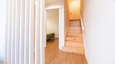 a hallway with white walls and wood floors and a staircase at Delightful Duplex by LovelyStay in Porto