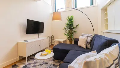 a living room with a blue couch and a tv at Delightful Duplex by LovelyStay in Porto