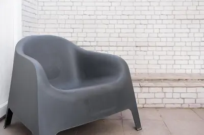 a gray chair sitting next to a white brick wall at GuestReady - Porto by Pilar Ridge in Vila Nova de Gaia
