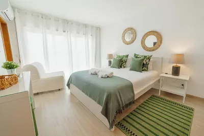 a white bedroom with a bed and a green rug at Rooftop Stylish by Hosty in Porto