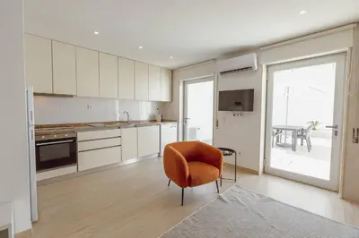 a kitchen with white cabinets and a chair and a table at Stylish Apartment With Terrace by Hosty in Porto