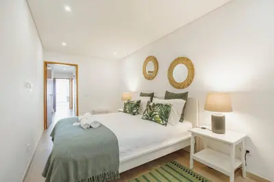 a white bedroom with a white bed and a table at Stylish Apartment With Terrace by Hosty in Porto