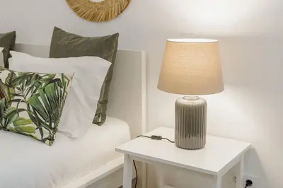 a lamp on a table next to a bed with pillows at Stylish Apartment With Terrace by Hosty in Porto