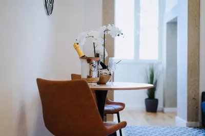 a dining room table with a vase of flowers and a chair at Exclusive Charm House in Porto
