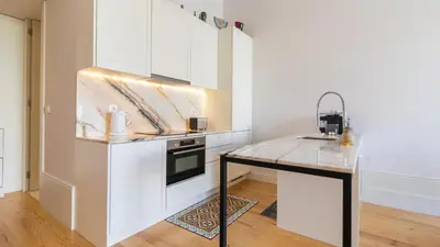 a kitchen with white cabinets and a counter top at Duque Flat - AC & Balcony by LovelyStay in Porto
