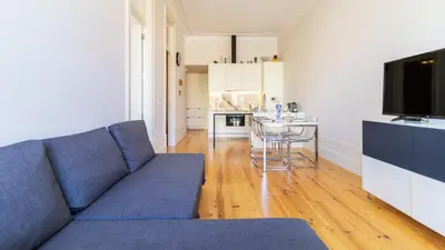 a living room with a blue couch and a kitchen at Duque Flat - AC & Balcony by LovelyStay in Porto
