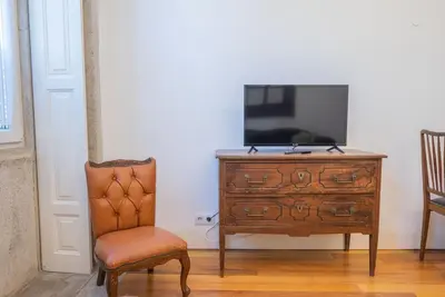 a tv sitting on top of a dresser next to a chair at So Truly Porto in Porto