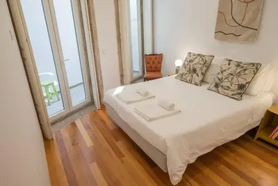 a white bed in a room with a large window at So Truly Porto in Porto