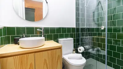 a green tiled bathroom with a sink and a toilet at Urban House Marquês by LovelyStay in Porto