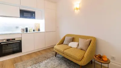 a living room with a yellow chair and a television at Urban House Marquês by LovelyStay in Porto